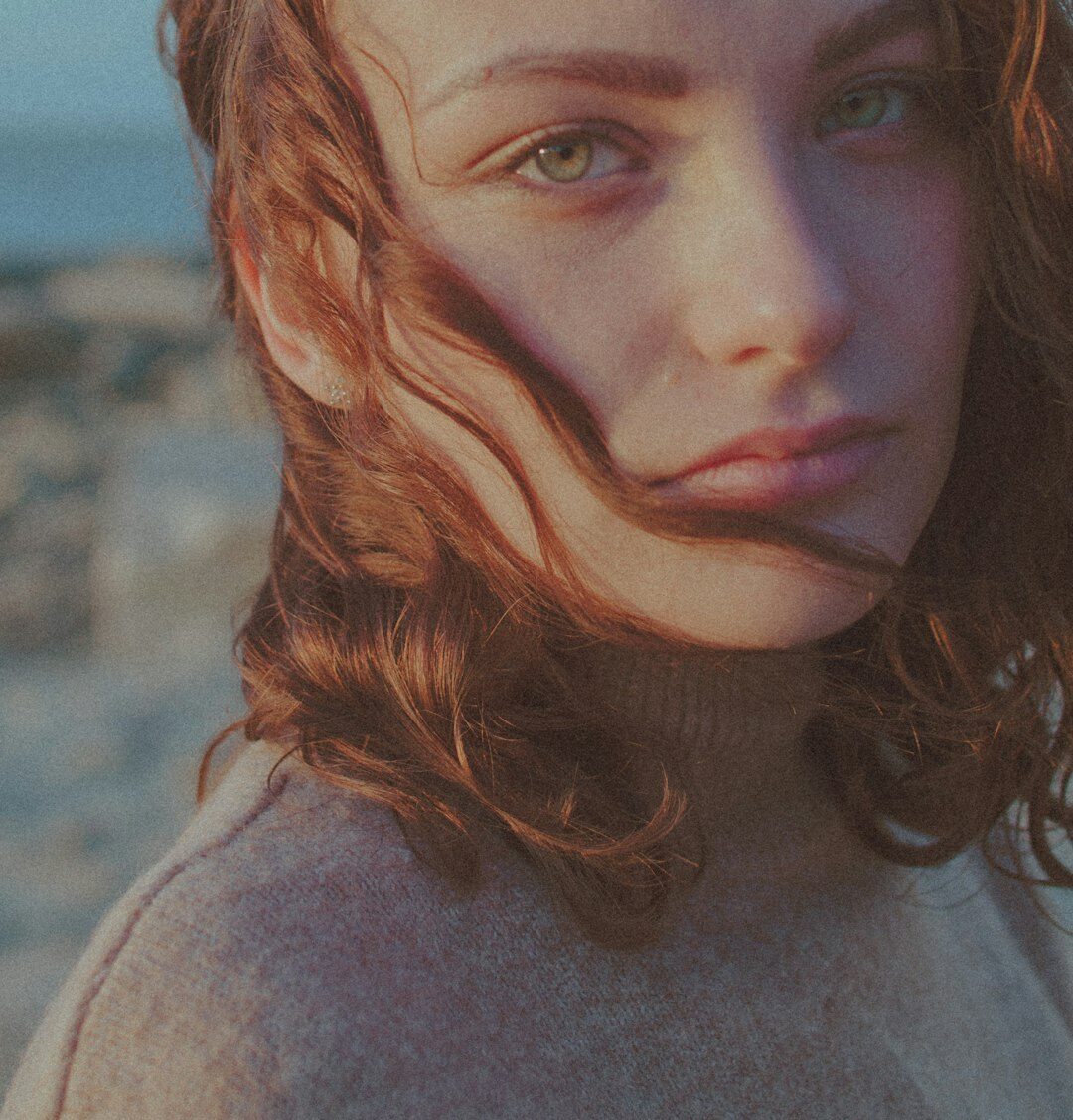 Brazilian woman with curly red hair near water, portrait